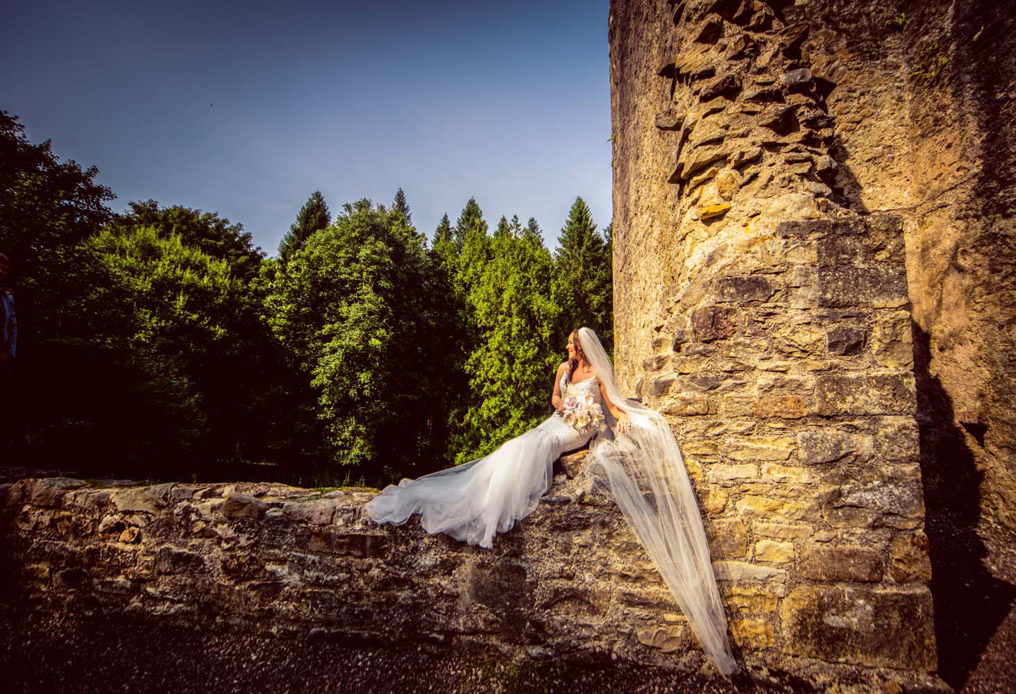 Bride laying on a wall at Castle Archdale Ruins - Tips for choosing your wedding photographer