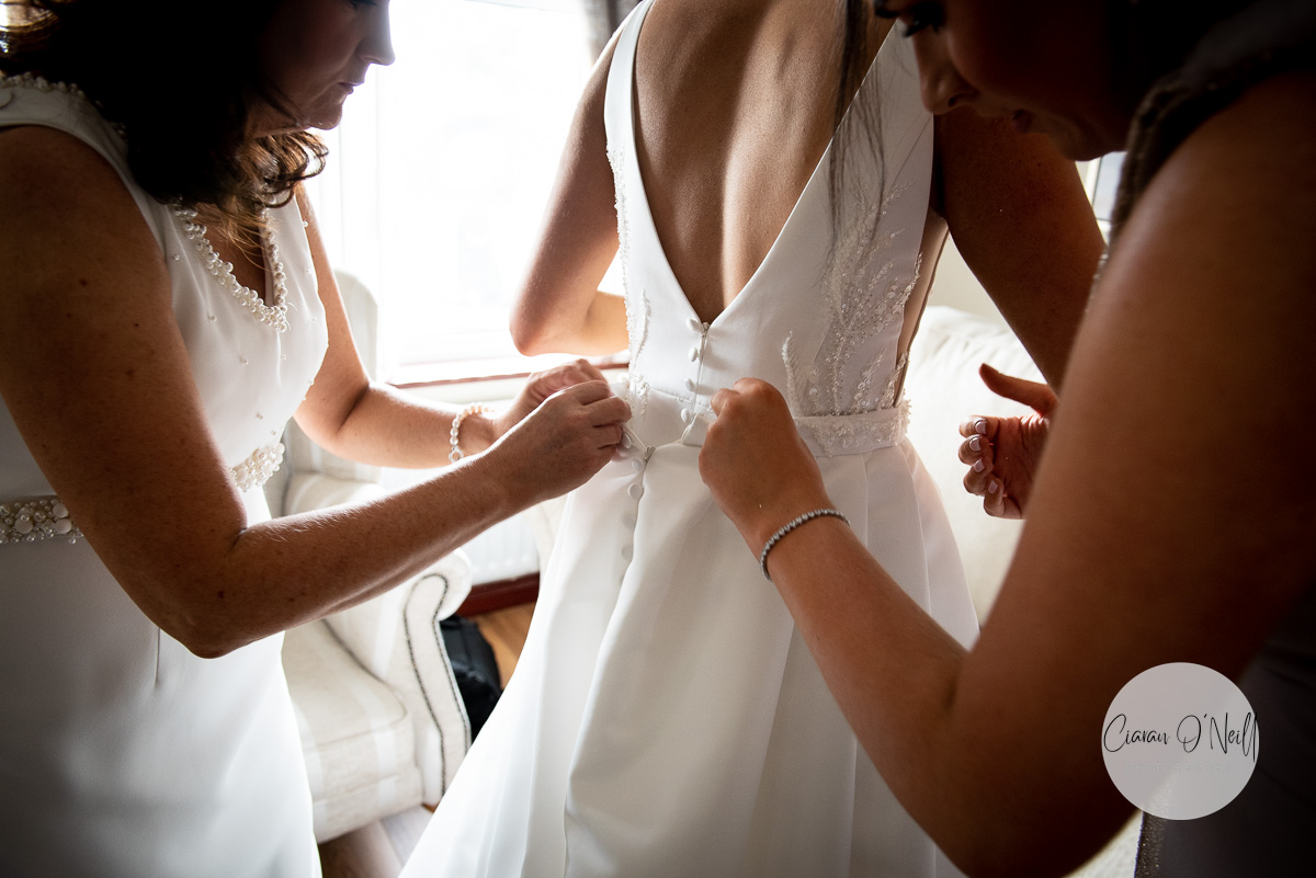 Bridemaids and Mother of the bride fixing the dress during the bridal prep