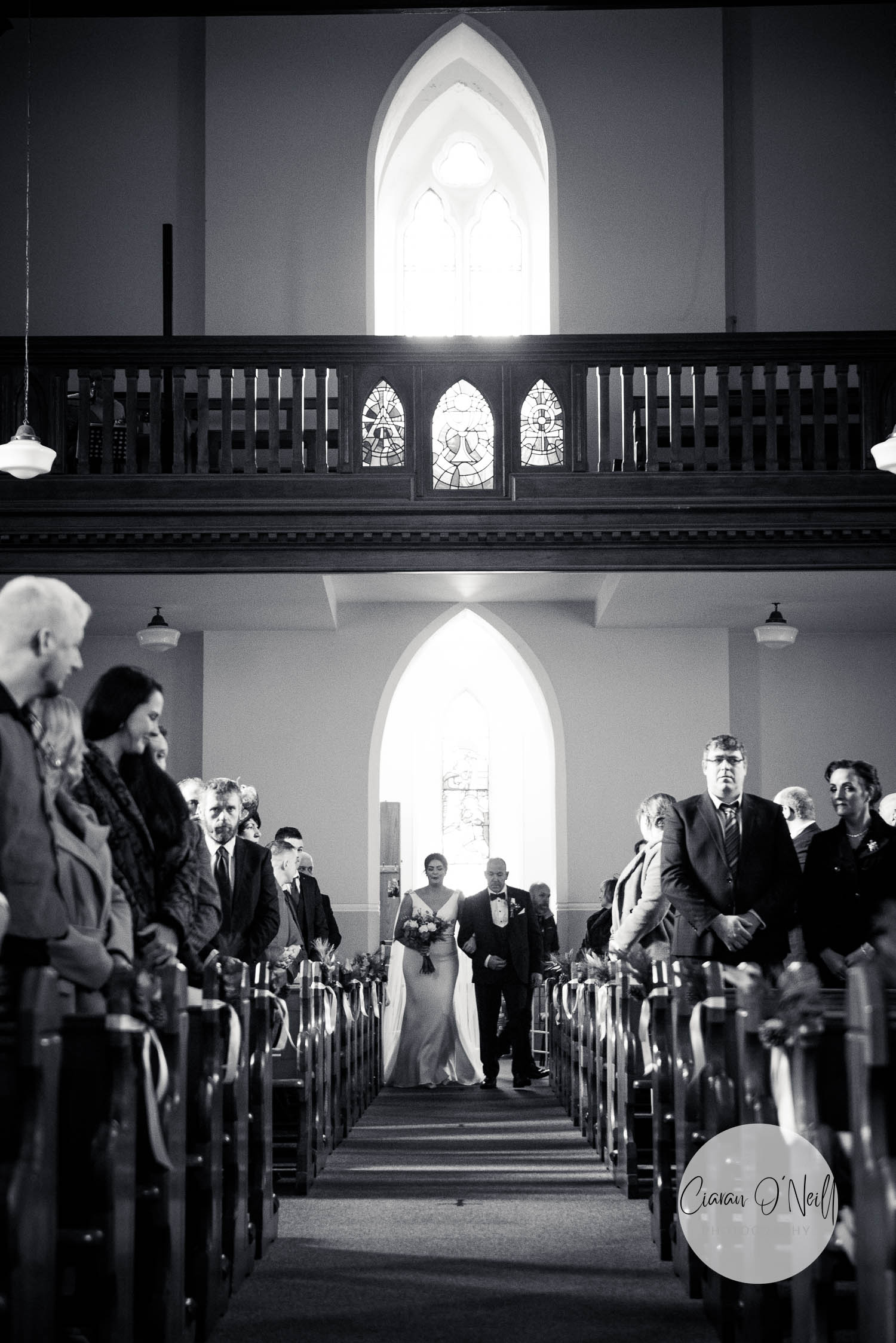 Father walks his daughter down the aisle of a large church