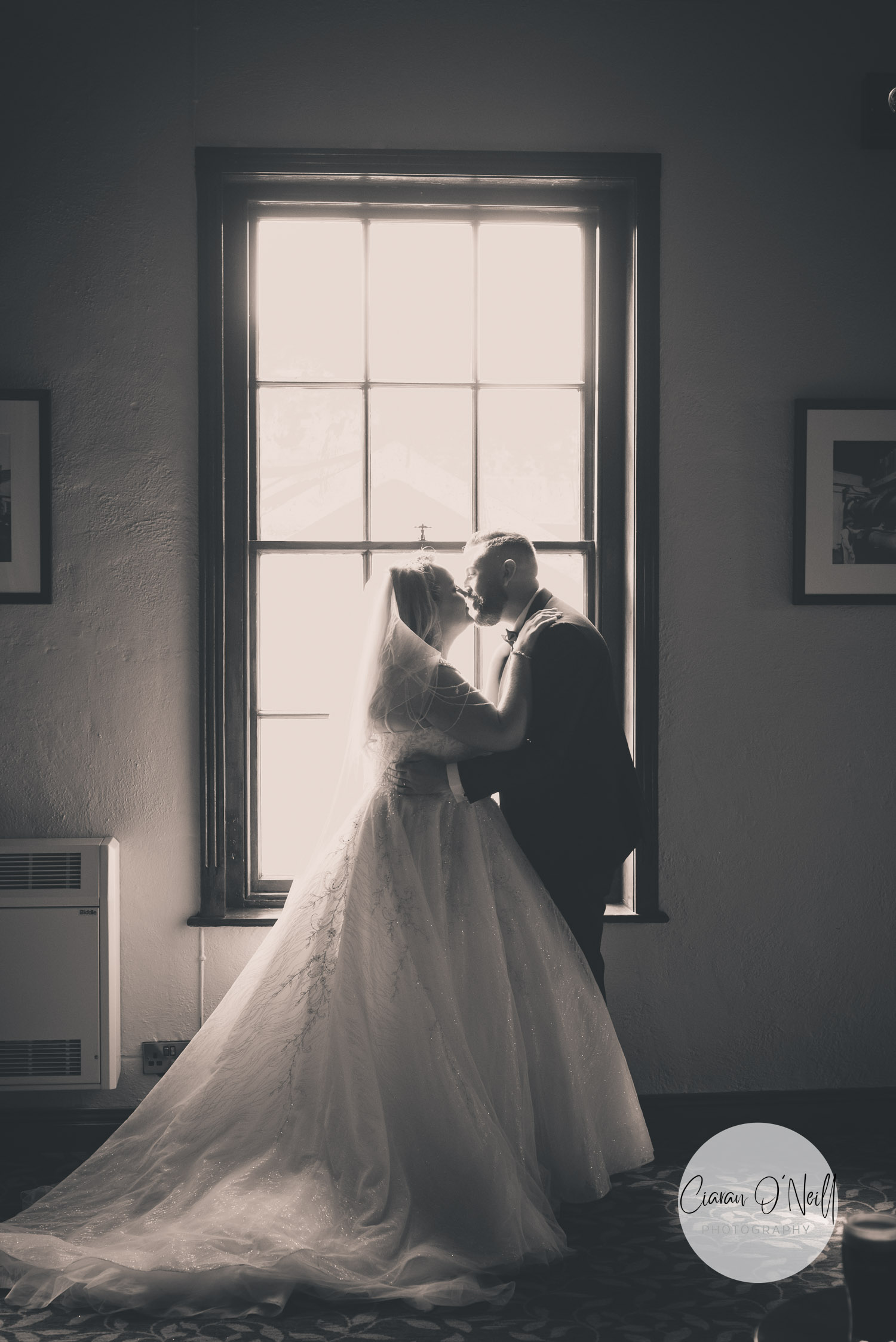 Bride & groom kissing in front of a window