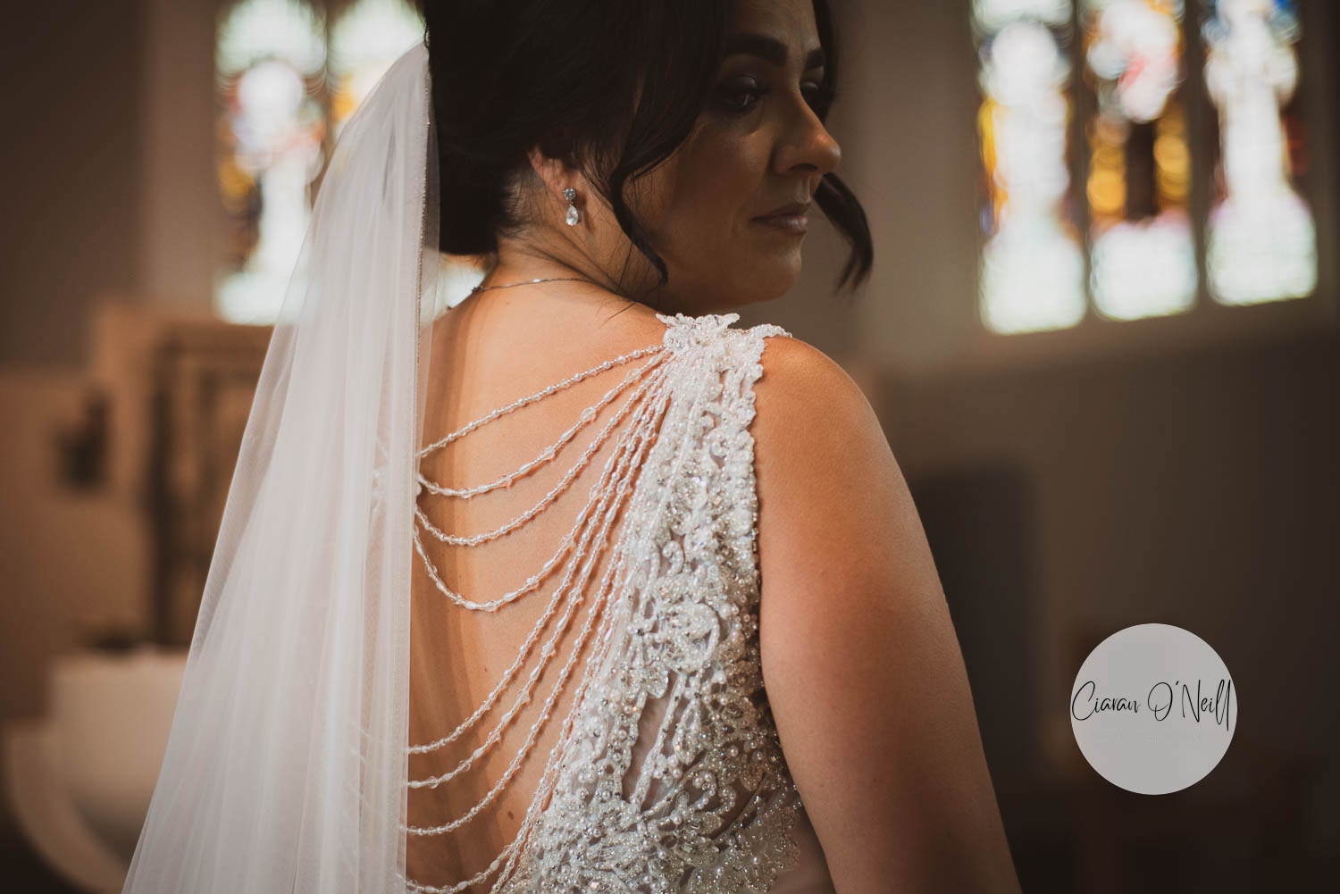 Beautiful bride pictured from the back showing intricate beadwork as she looks over her shoulder