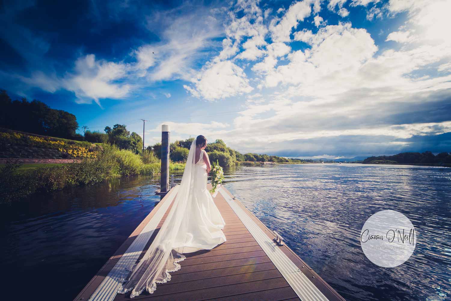 Bride standing on a pier looking away towards a lake at the Killyhevlin Hotel