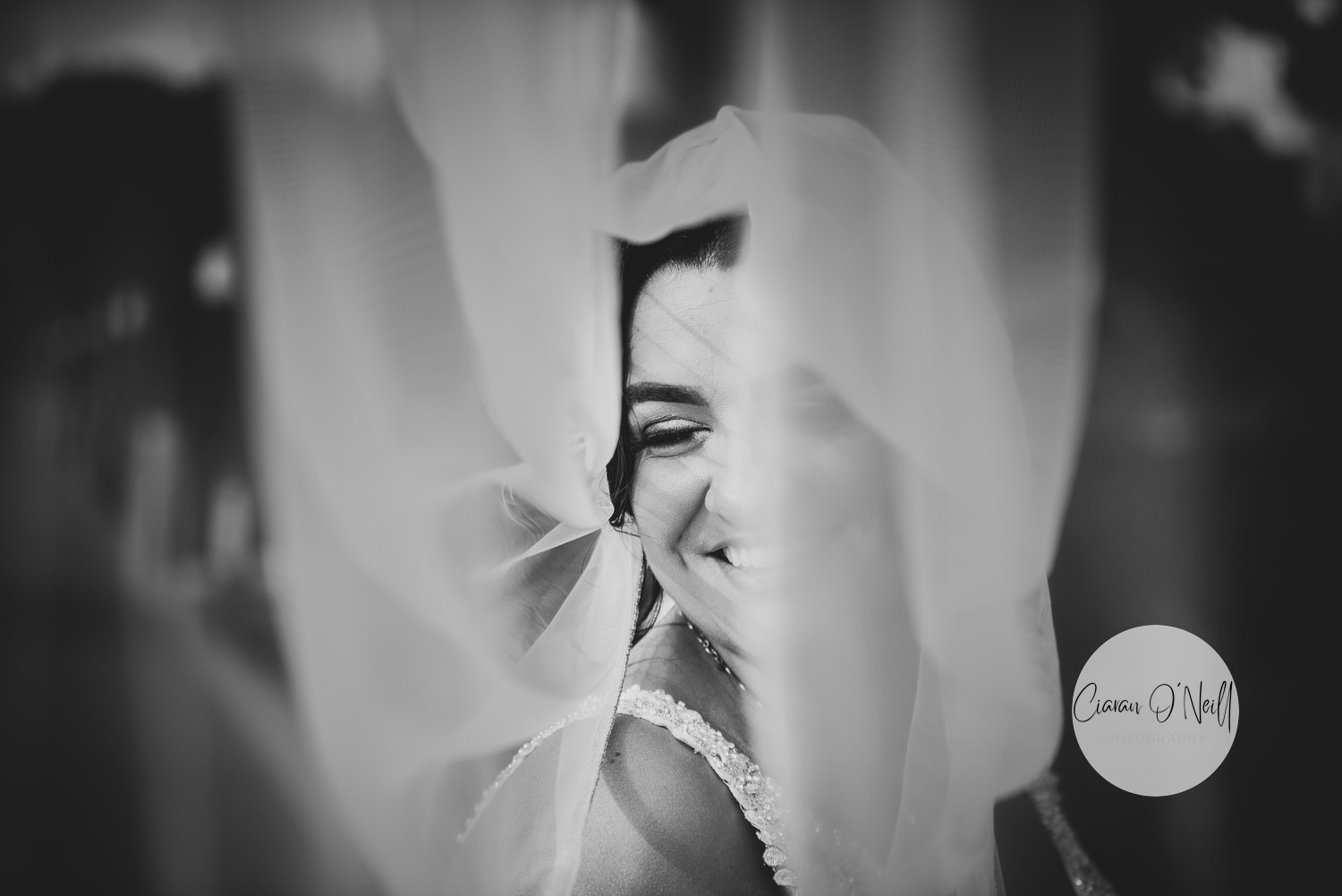 Black and white photo of bride looking through a an opening in her veil
