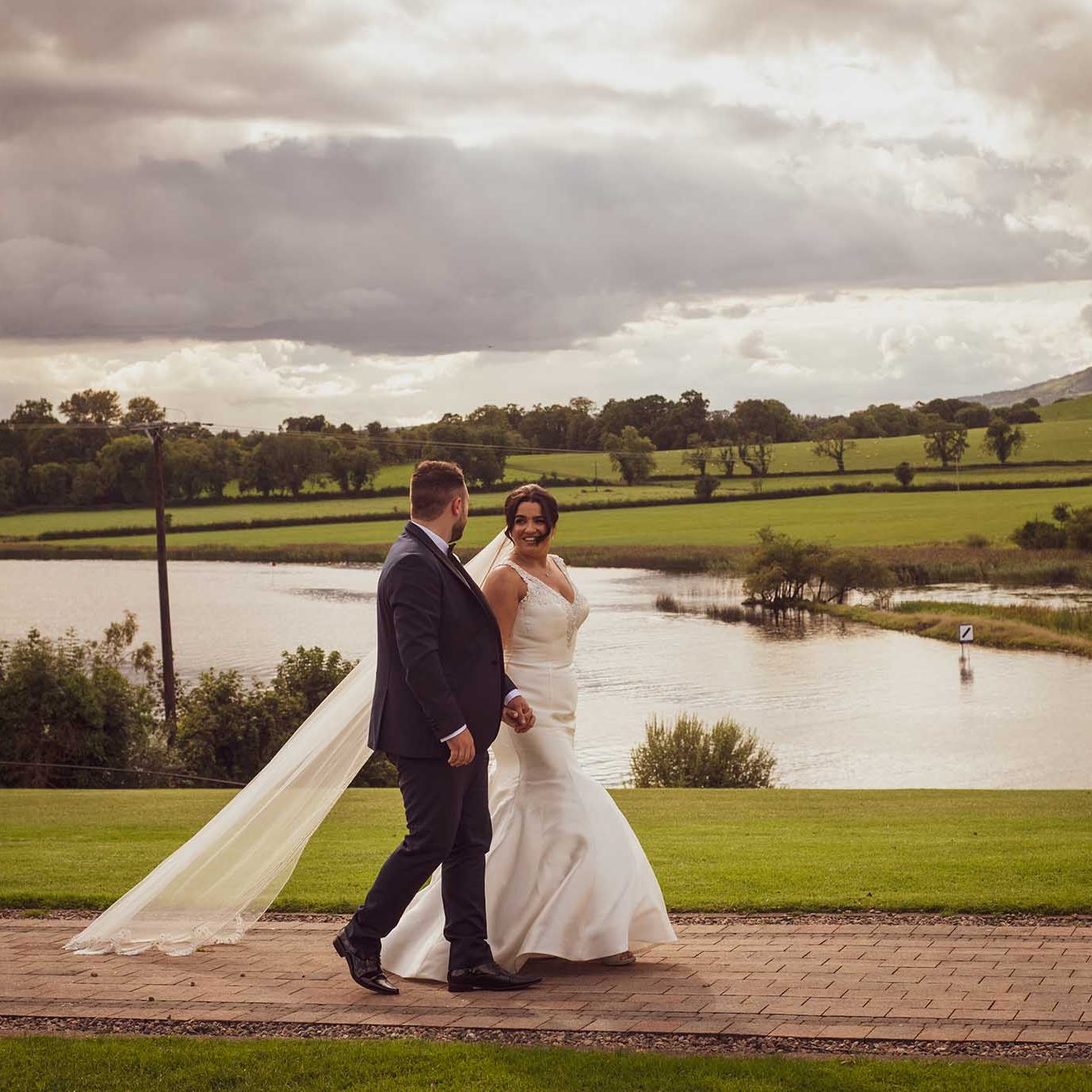Romantic bride and groom walking past lake at Killyhevlin hotel Fermanagh