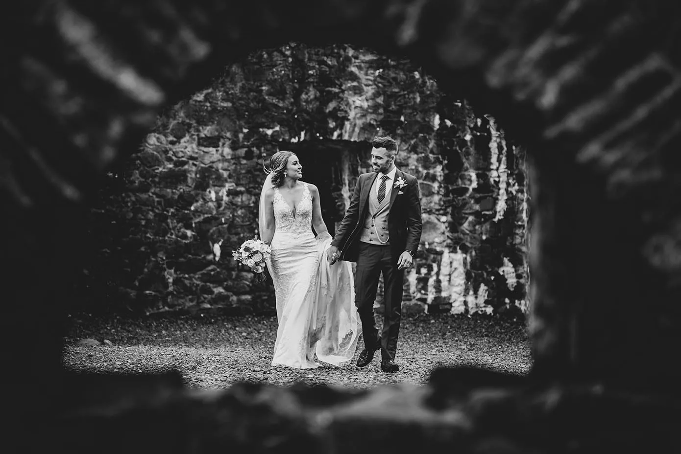Aoife & Conor walking through arch at Carlingford Ruins - Wedding Photography Northern Ireland
