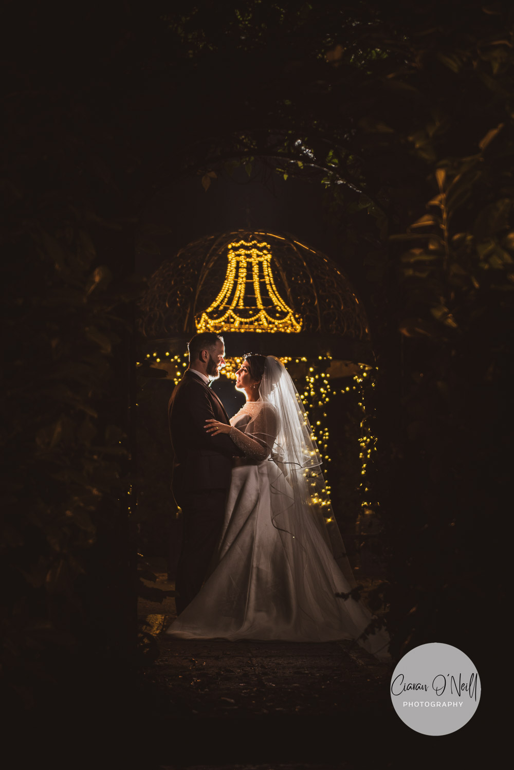 Bride and groom in front of gazebo Cabra Castle hotel at night