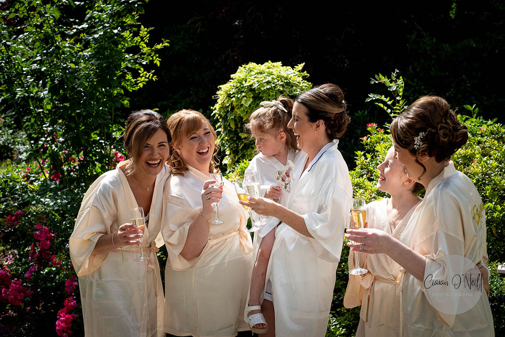 Bridal party laughing and drinking champagne on the morning of the wedding