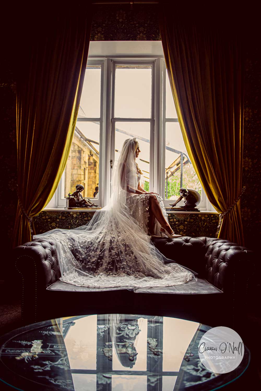 Bride sitting in window with reflection in glass table Cabra Castle Ciaran O'Neill Photography