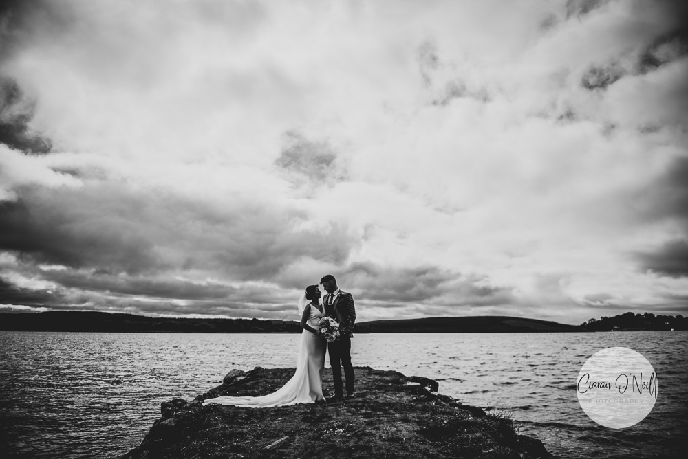 Bride & groom looking at each other, standing at the edge of Lower Lough Erne