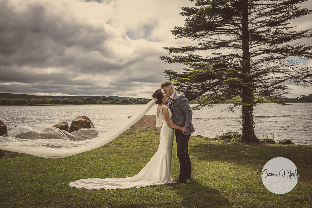 Bride & groom standing at the side of a lough
