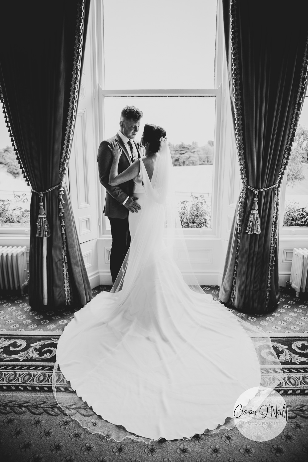 Bride & Groom looking at each other whilst standing in front of a window in the Manor House