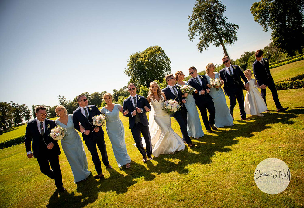 Bridal party walking with linked arms at Darver Castle