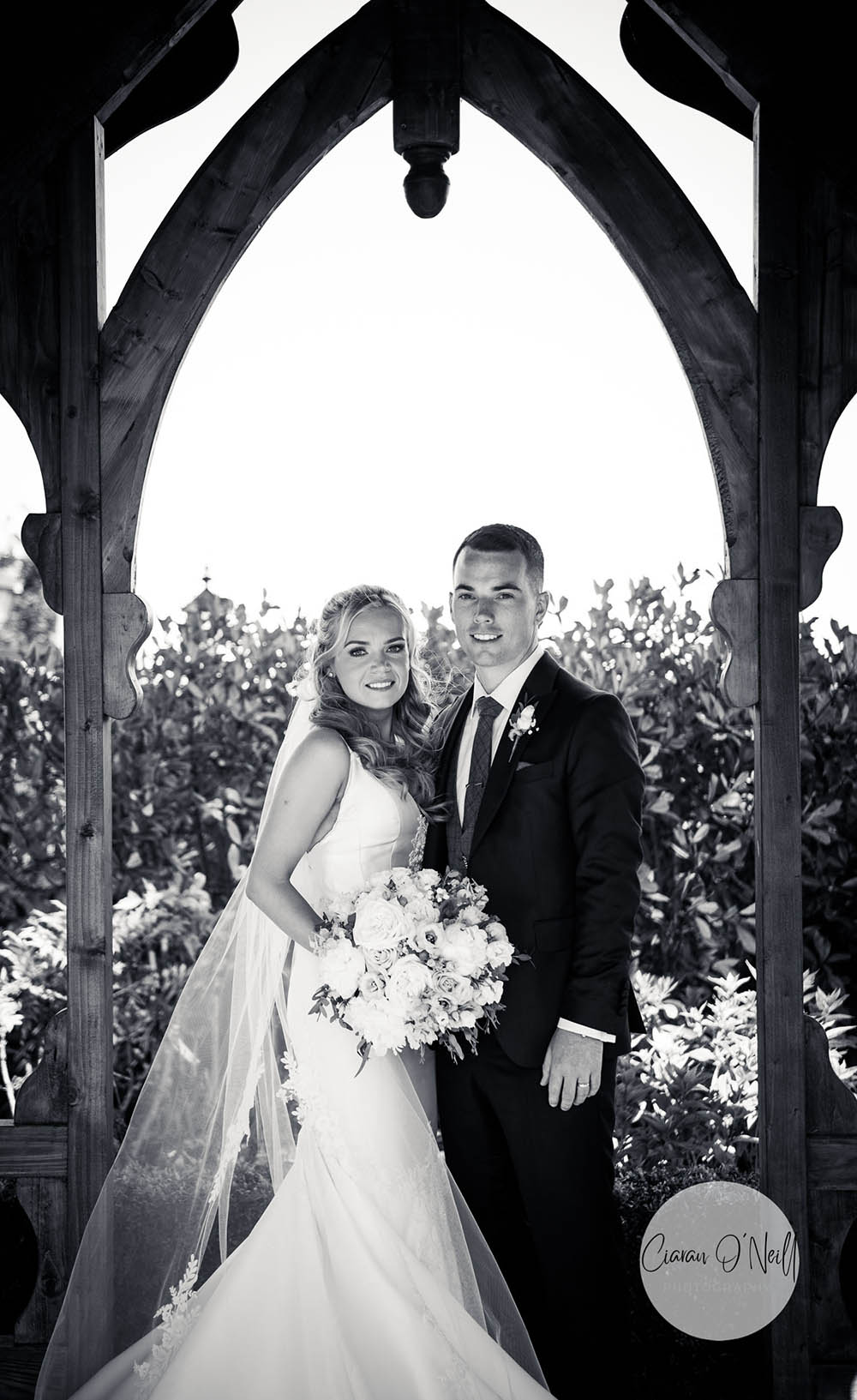 Bride and groom in wooden archway in B&W Darver Castle
