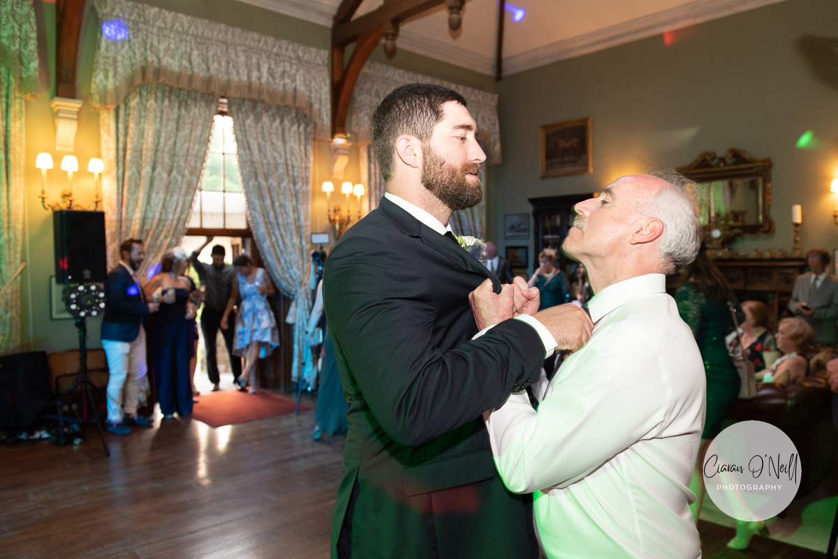 Groom and his father in law playfully grab each other before the first dance