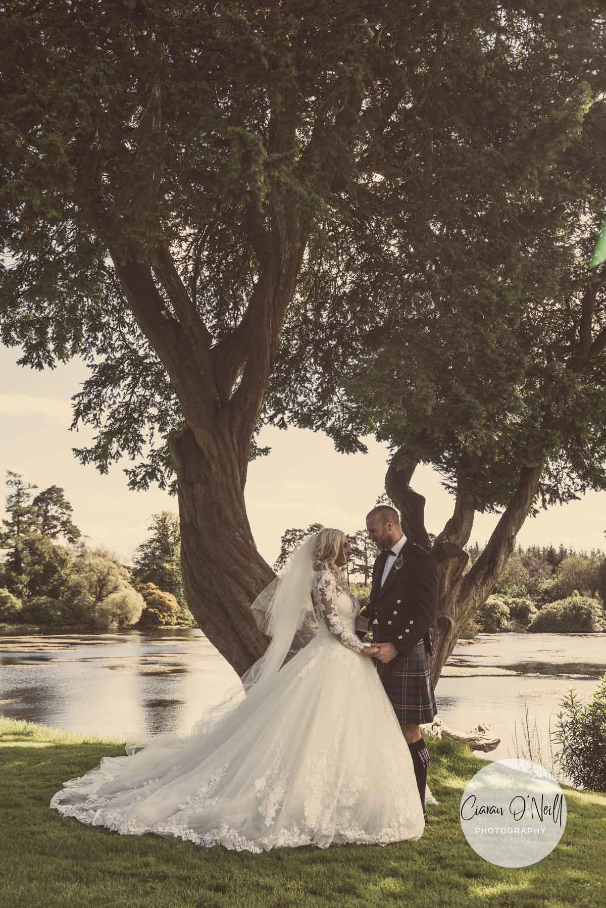 Bride & Groom cuddle beside the lake at their Castle Leslie Wedding