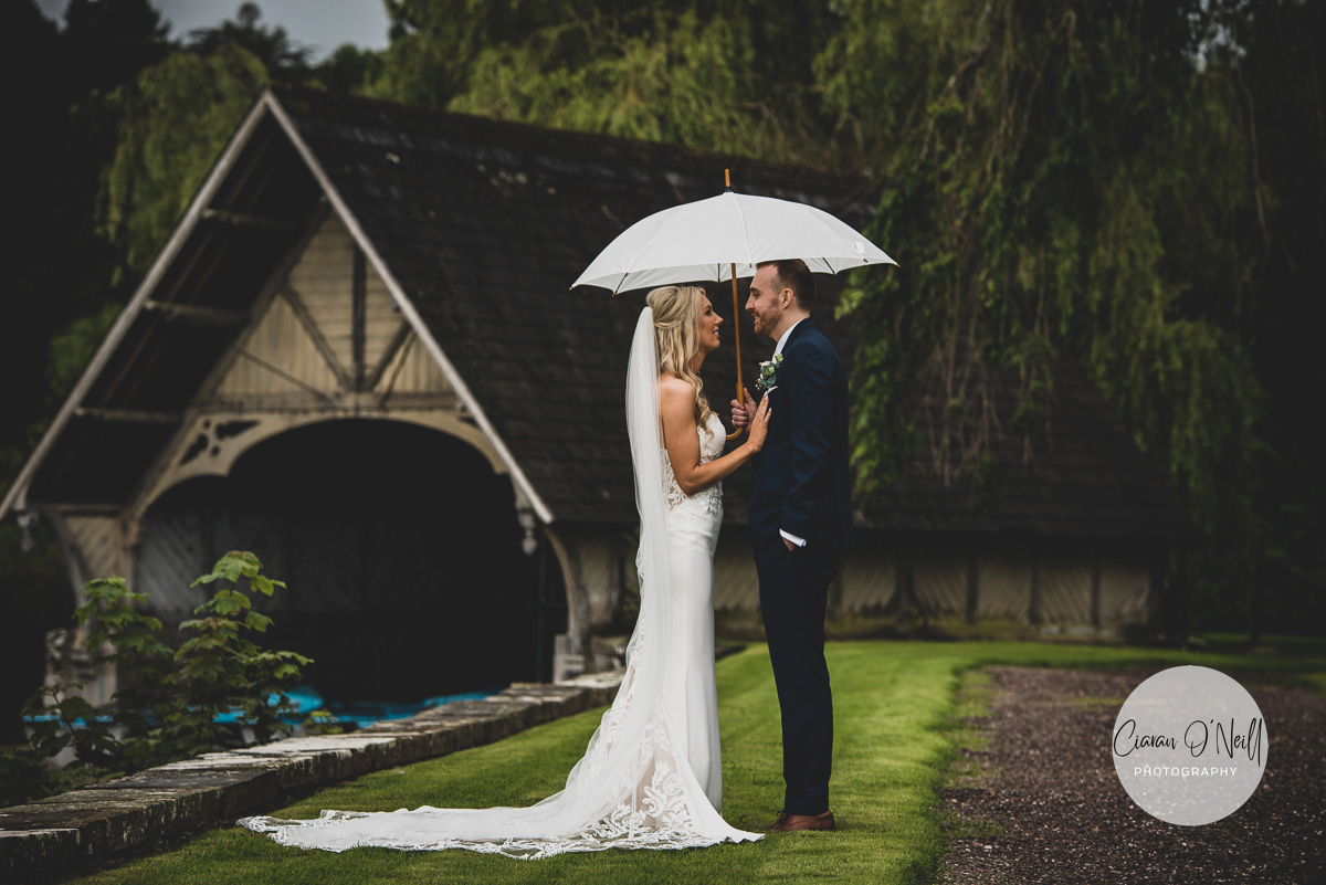 A newly married couple smooch under an umbrella