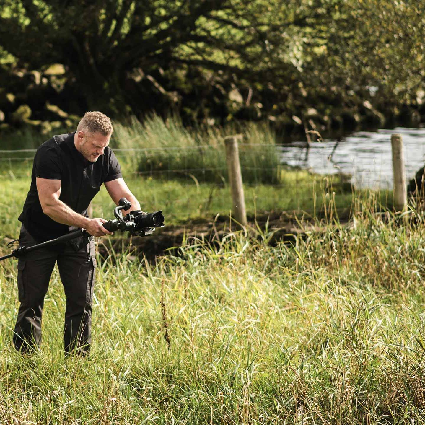 Bobby from Motion Media shooting a video whilst in long grass at the edge of a lake