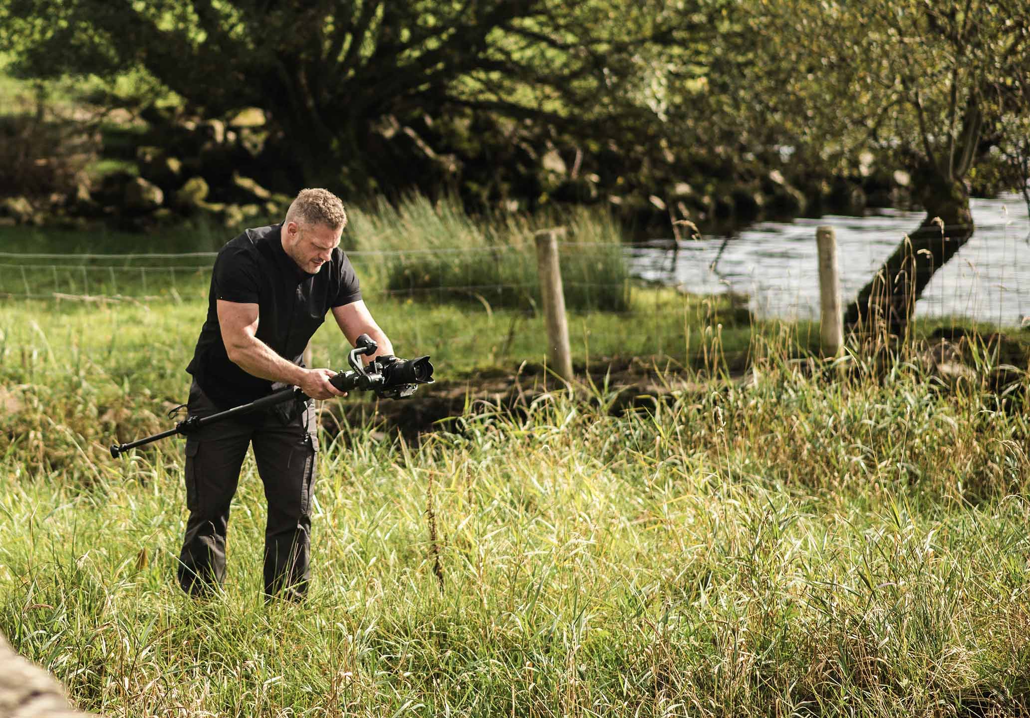 Bobby from Motion Media shooting a video whilst in long grass at the edge of a lake