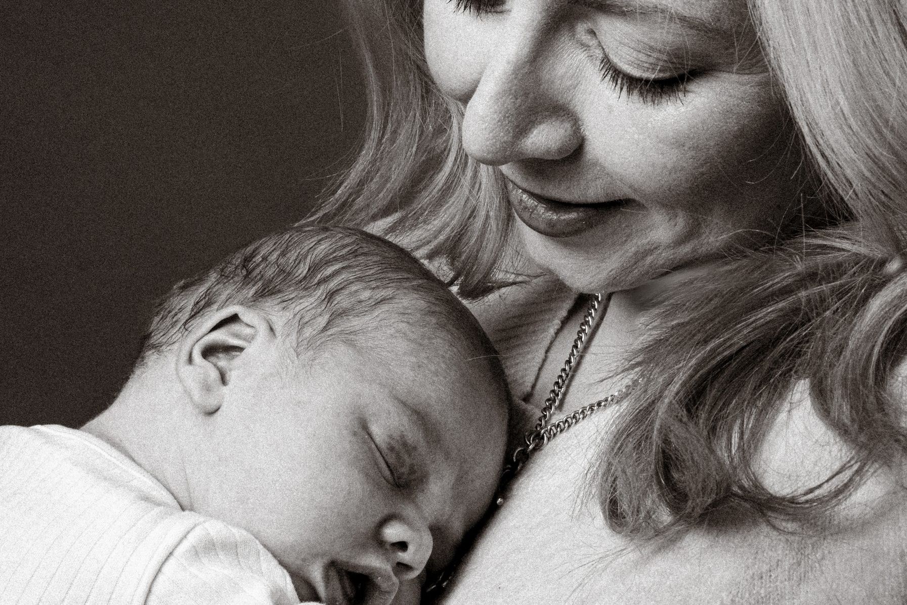 Blonde haired mum holding newborn baby in black and white image by Ciaran O'Neill