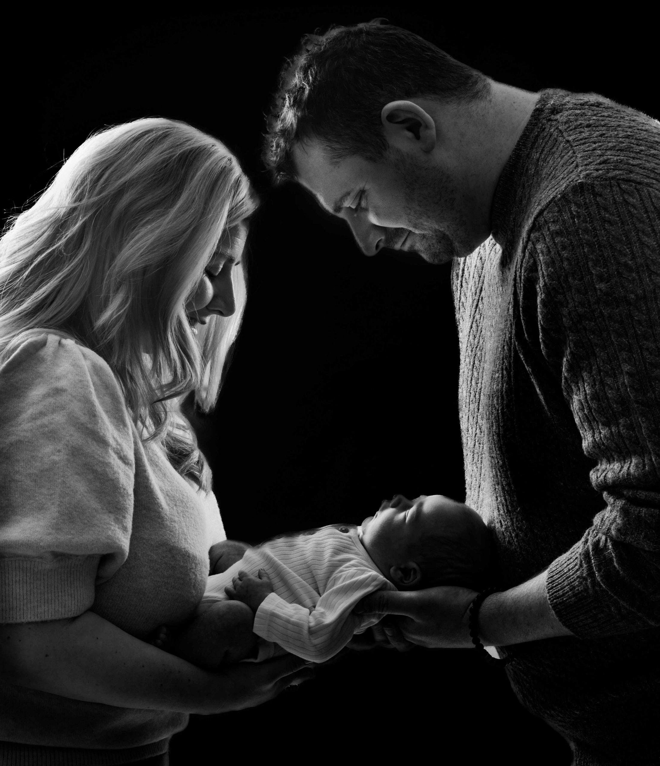 black and white photo of parents looking lovingly at their newborn baby