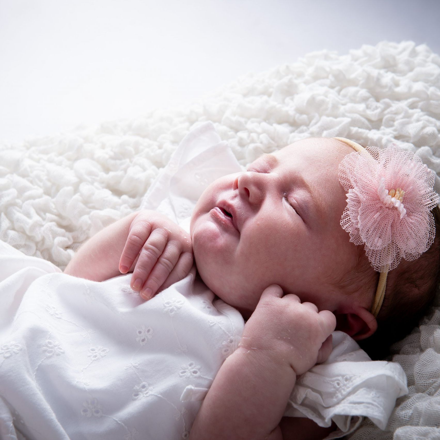new born baby girl with a pink flower in her hair