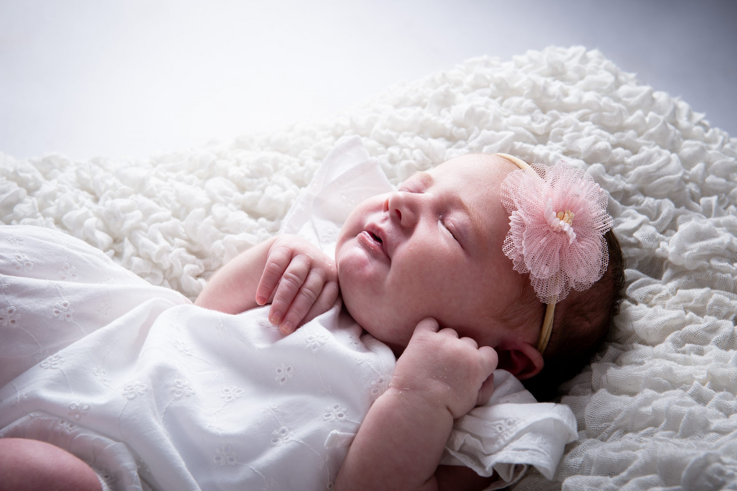 new born baby girl with a pink flower in her hair